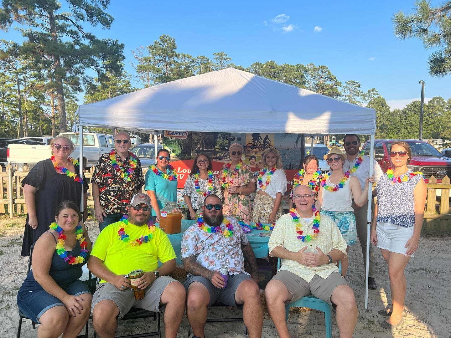 A group of people posing under a tent at the Business After Hours networking event on the beach.