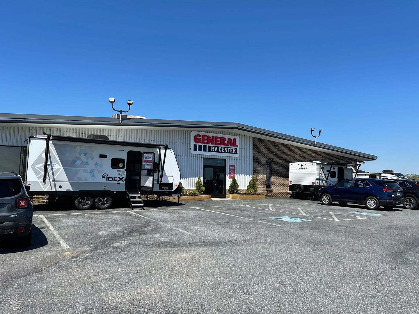 Two rvs parked in front of a building hosting America's Largest RV Show, organized by General RV Center.