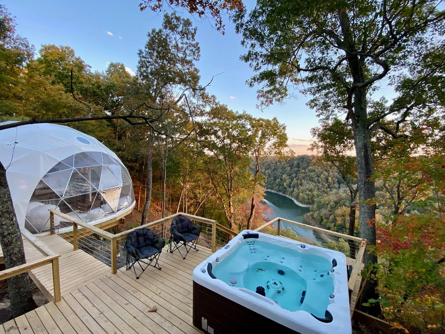A glamping igloo on top of a deck with a hot tub.