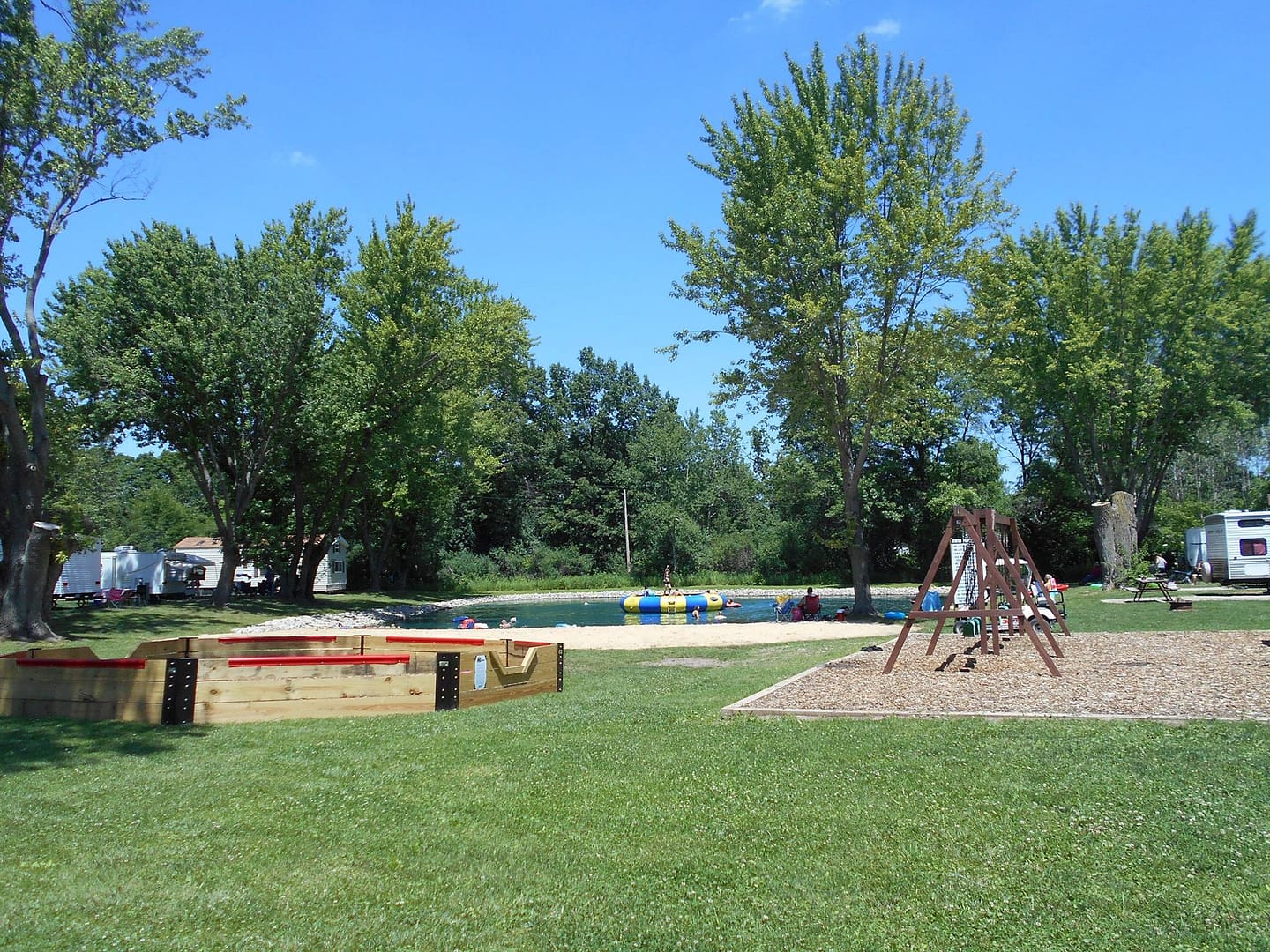 Explore the Virtual Tour of Badgerland Campground, featuring a grassy area with a swing set.