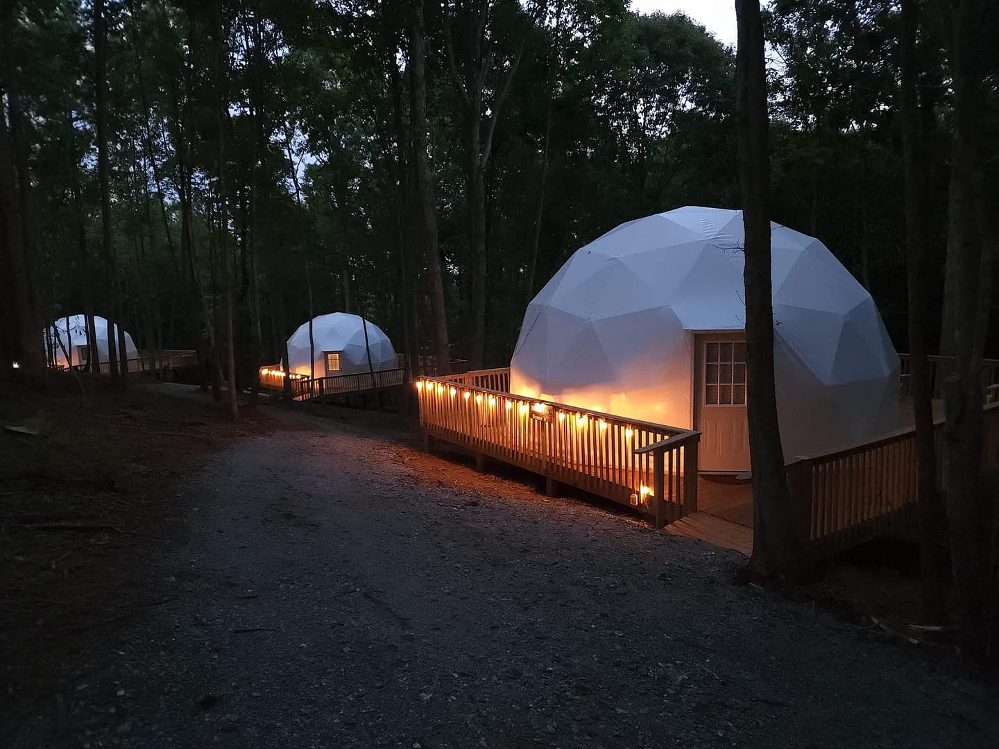 A group of white dome tents in a North Carolina campground at night.
