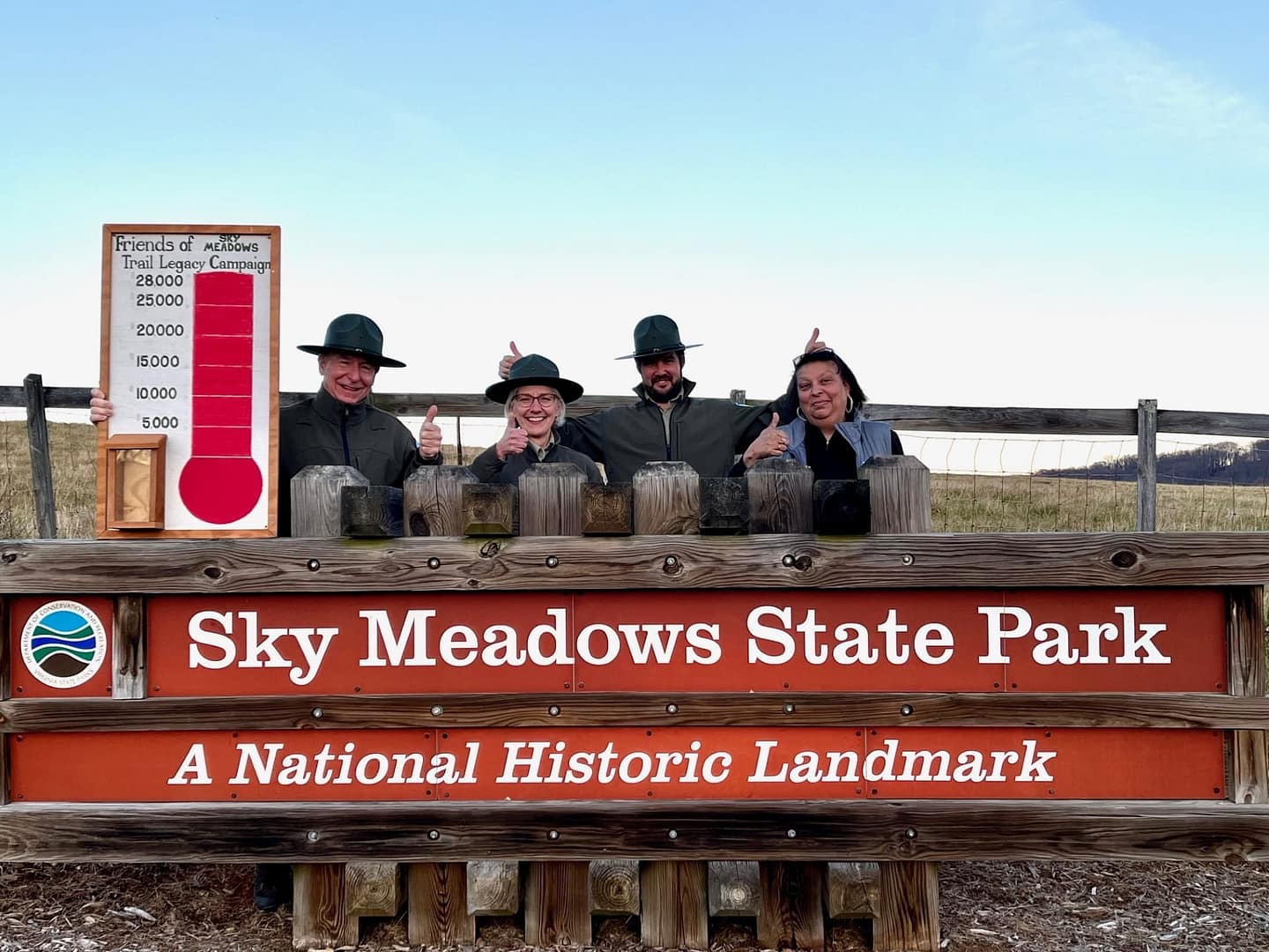 A group of people standing in front of a sign that says Sky Meadows State Park while fundraising for Lost Mountain Trail.