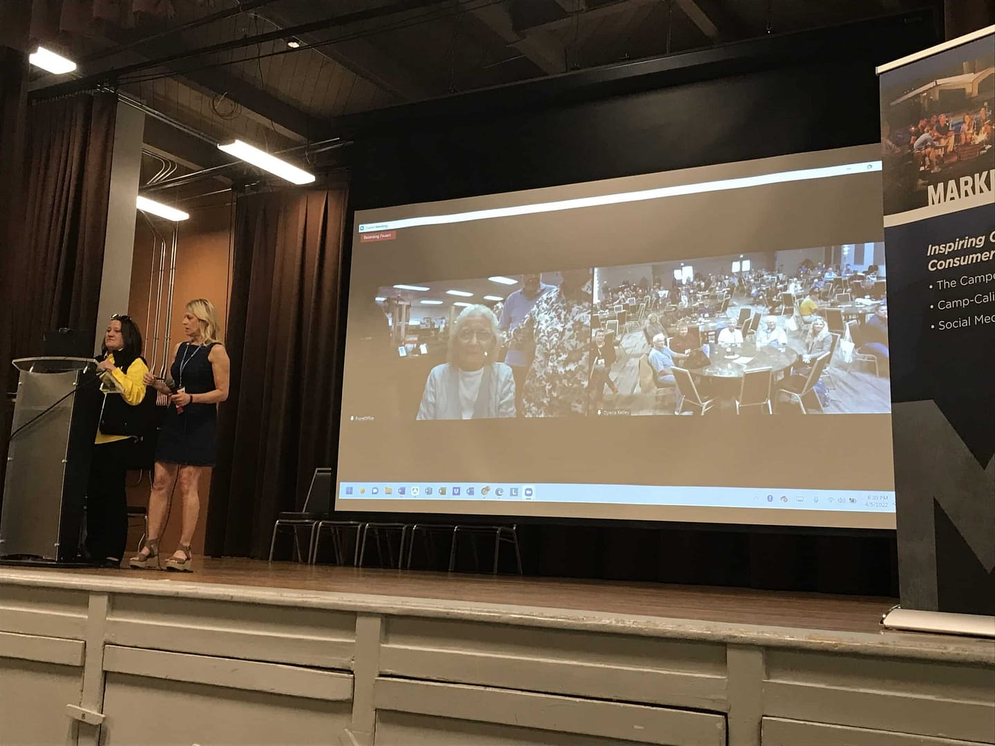 Two women standing at a podium in front of a screen at the Orangeland RV Resort.