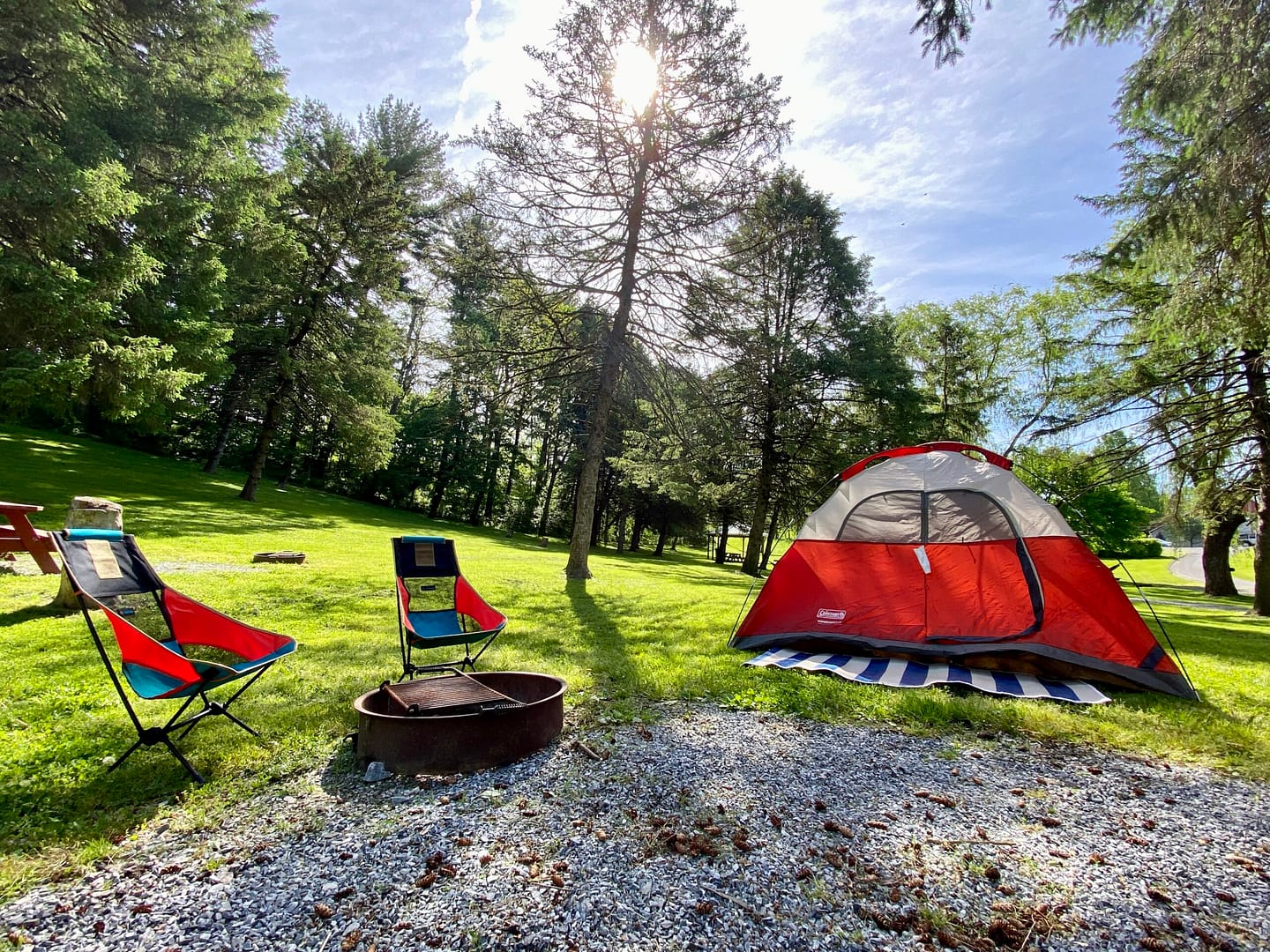 A tent set up in a grassy area at Hersheypark Camping Resort with a fire pit.