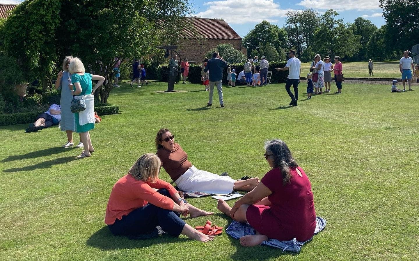 A group of people sitting on the grass in front of a building.