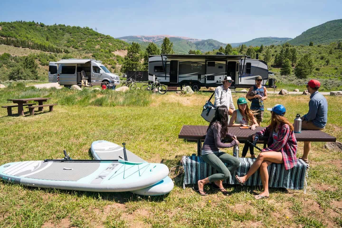 A group of people sitting around a table with an RV.