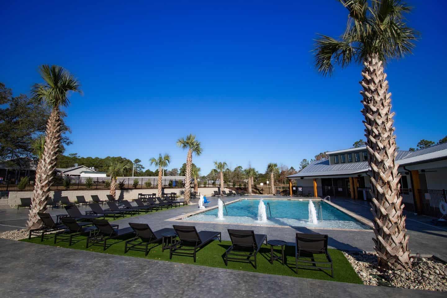 A luxurious pool area with lounge chairs and palm trees, located in a luxury RV resort in North Carolina.