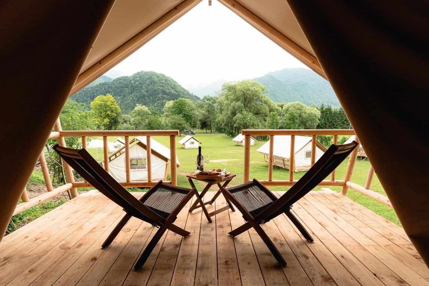 Two luxurious chairs on the deck of a Slovenian tent, nestled amidst the stunning nature of a mountain.