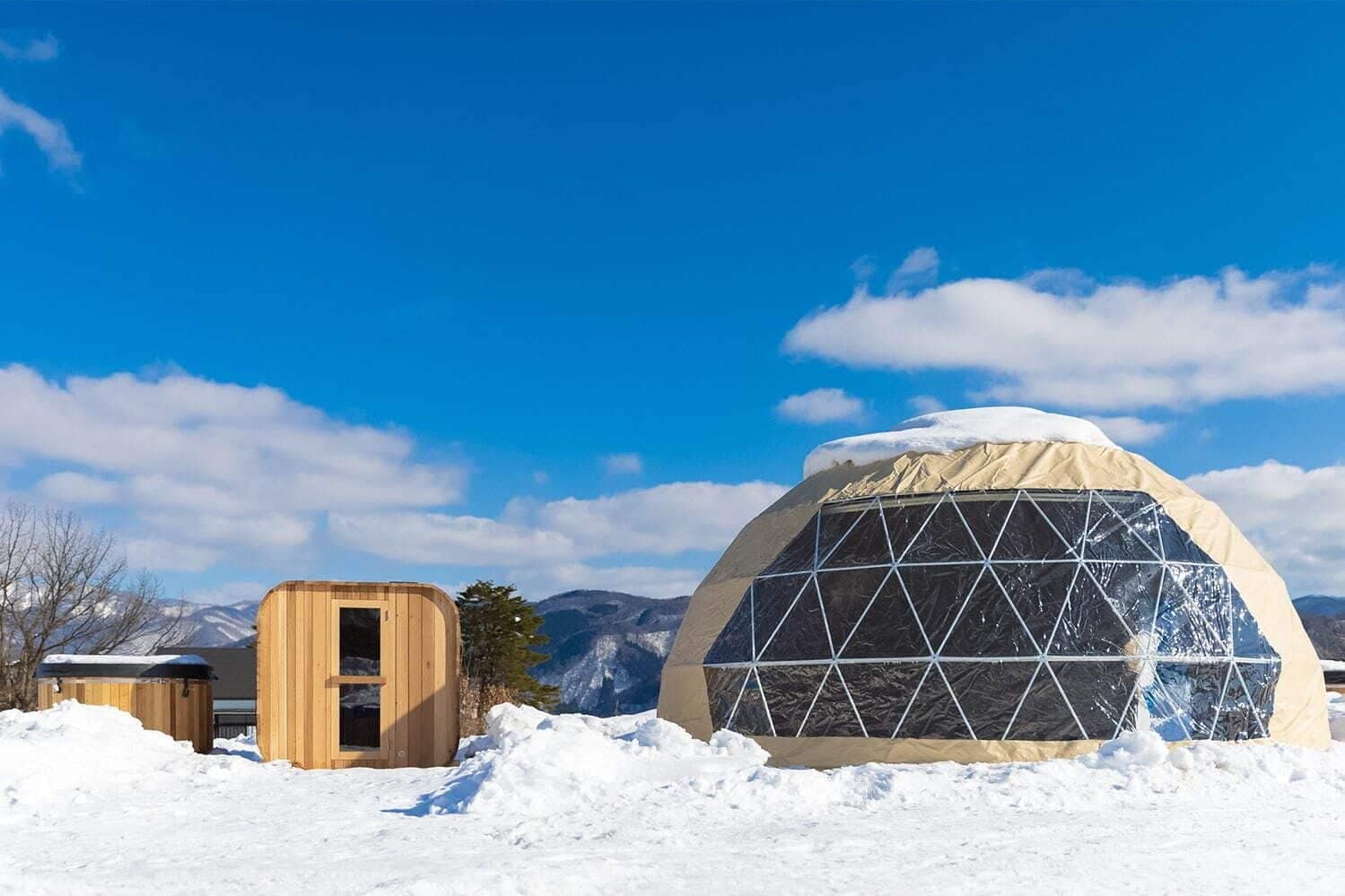 A Japanese-inspired igloo sitting on top of a snow covered mountain, offering a unique glamping experience with igloo tents.