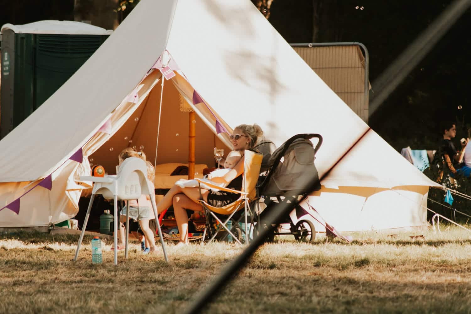 Glamping in the UK: A woman and child enjoying the outdoors while sitting in comfortable chairs outside a tent.