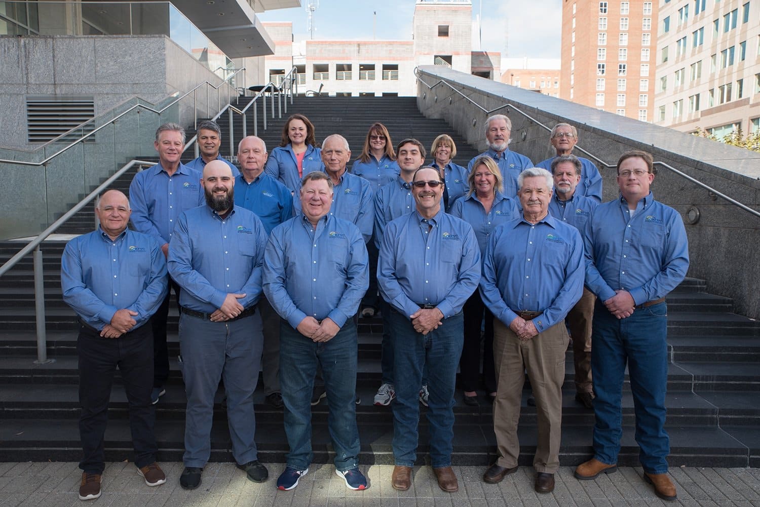 A group of new board members in blue shirts standing on steps.