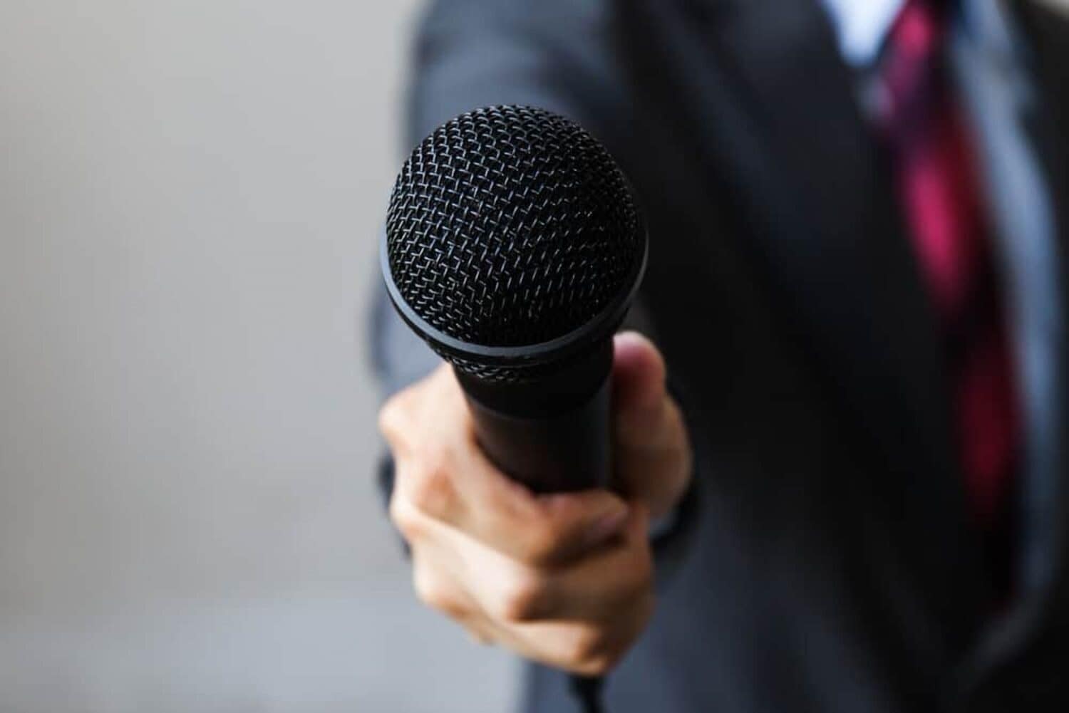 A man in a suit holding a microphone gives public comments on the Water System Project by the National Park Service.