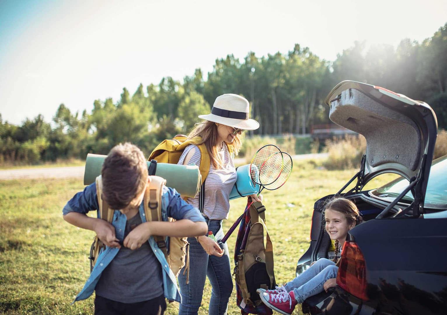 A woman and her children are opening the trunk of a car to begin their camping adventure at Kentucky Park.