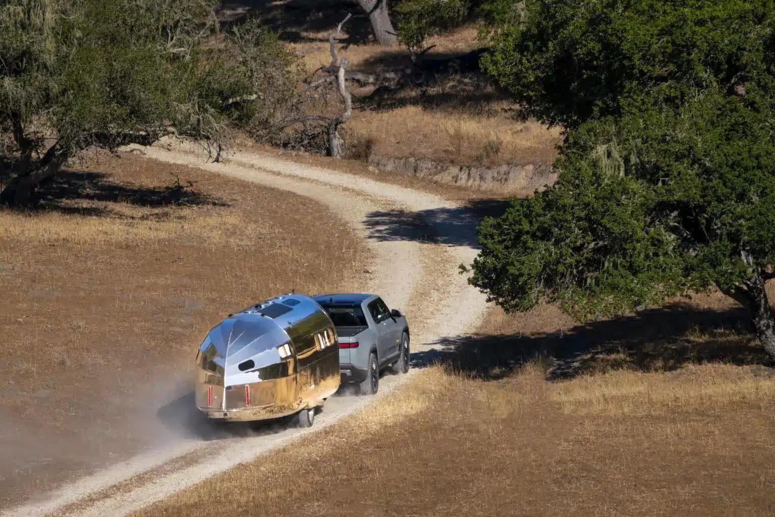 A luxurious Bowlus airstream trailer is effortlessly cruising down a dirt road.