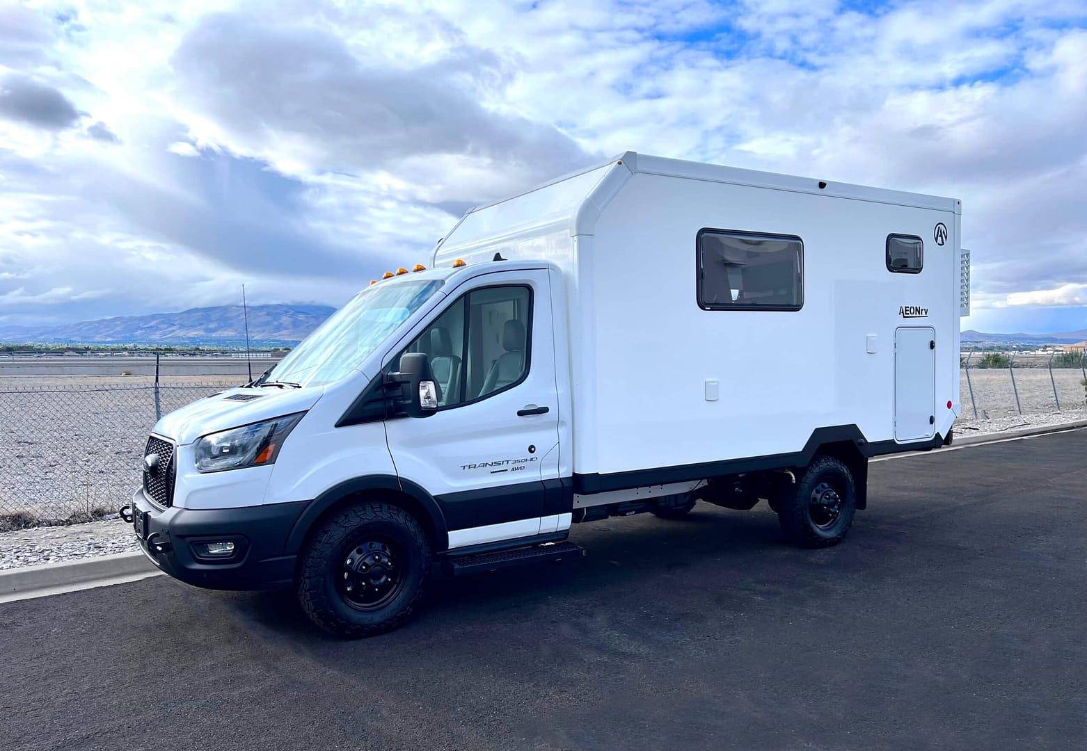 A white RV, specifically the AEONrv 2023 model, parked on the side of the road.