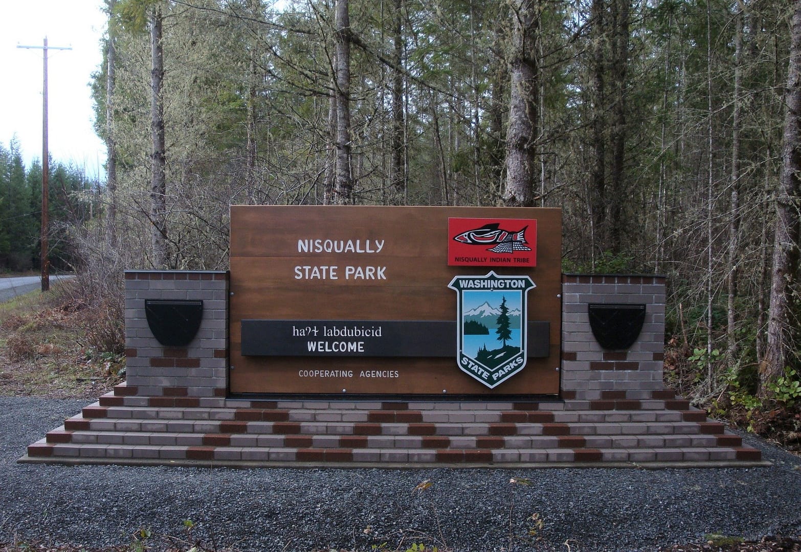 A sign in front of a wooded area announces the New State Park.