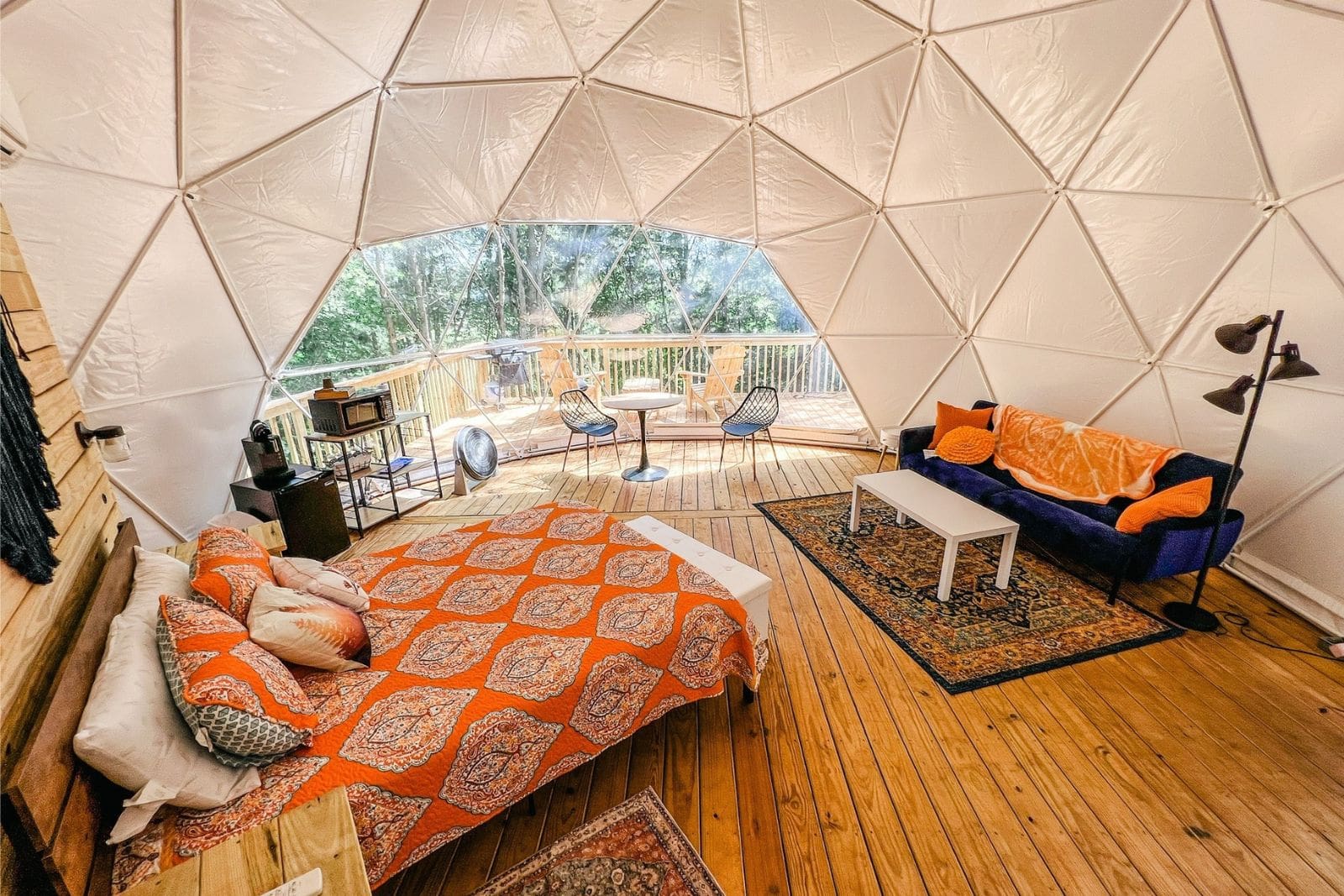 A living room inside a dome, now a trending Campspot for Spring Break Camping, with a couch and a bed.
