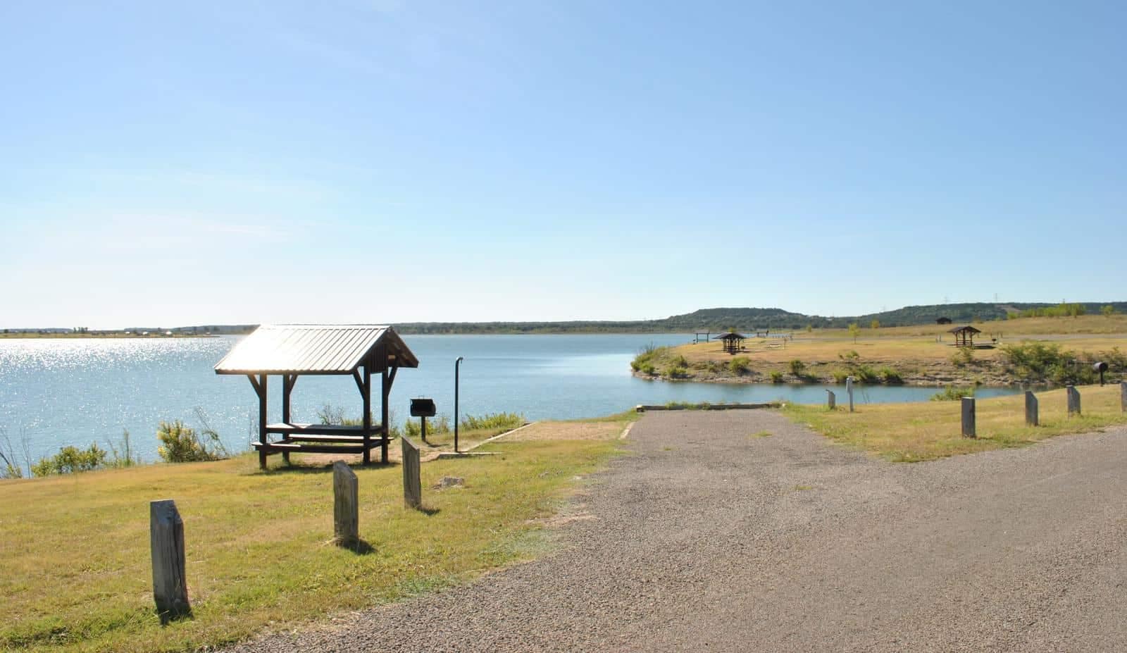 A road leading to Stillhouse Hollow Lake, managed by the U.S. Army Corps of Engineers within the Fort Worth District, featuring a picnic table.