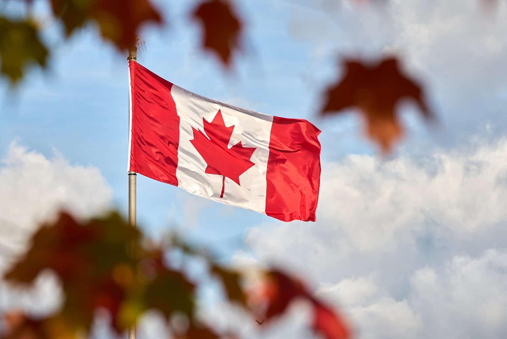 A Canadian flag flutters in the wind, showcasing the pride of Canadian travel and tourism.