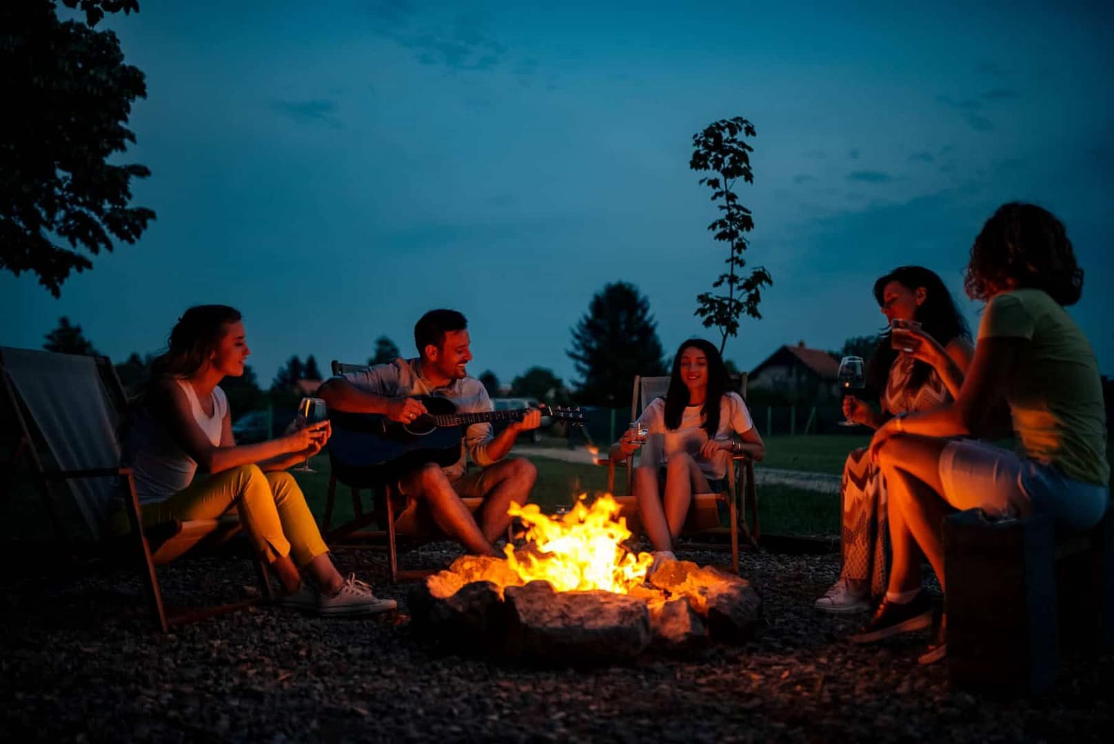 Friends sitting around a campfire at night - campfire stock pictures, royalty-free photos & images.