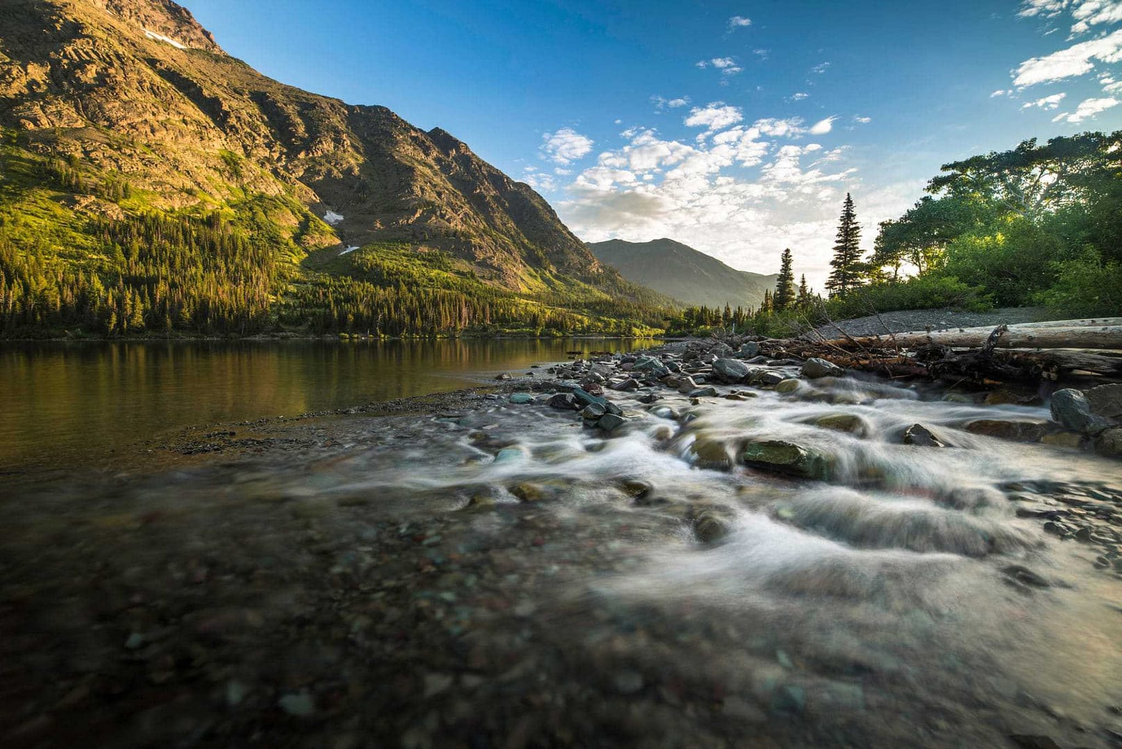 University of Montana research factors in choosing campsites for campers along a mountain stream flowing through a rocky area with mountains in the background.