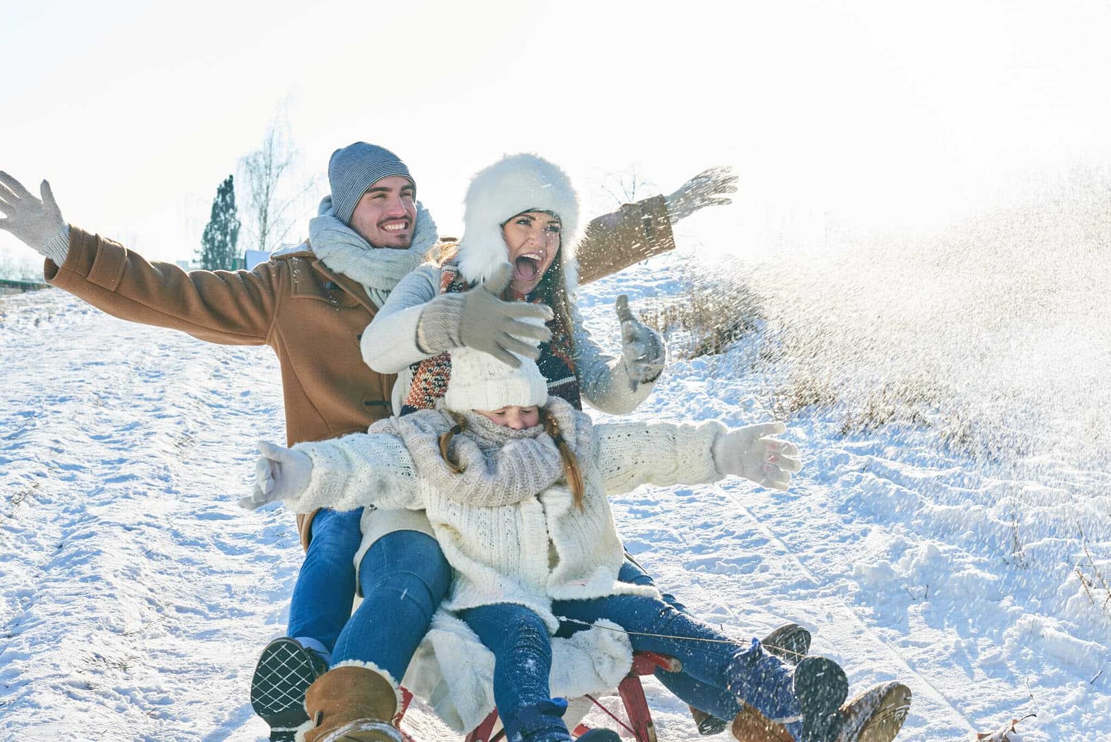 A family is having Winter Wonderland Adventures by riding a sled in the snow at Duck Mountain Provincial Park.
