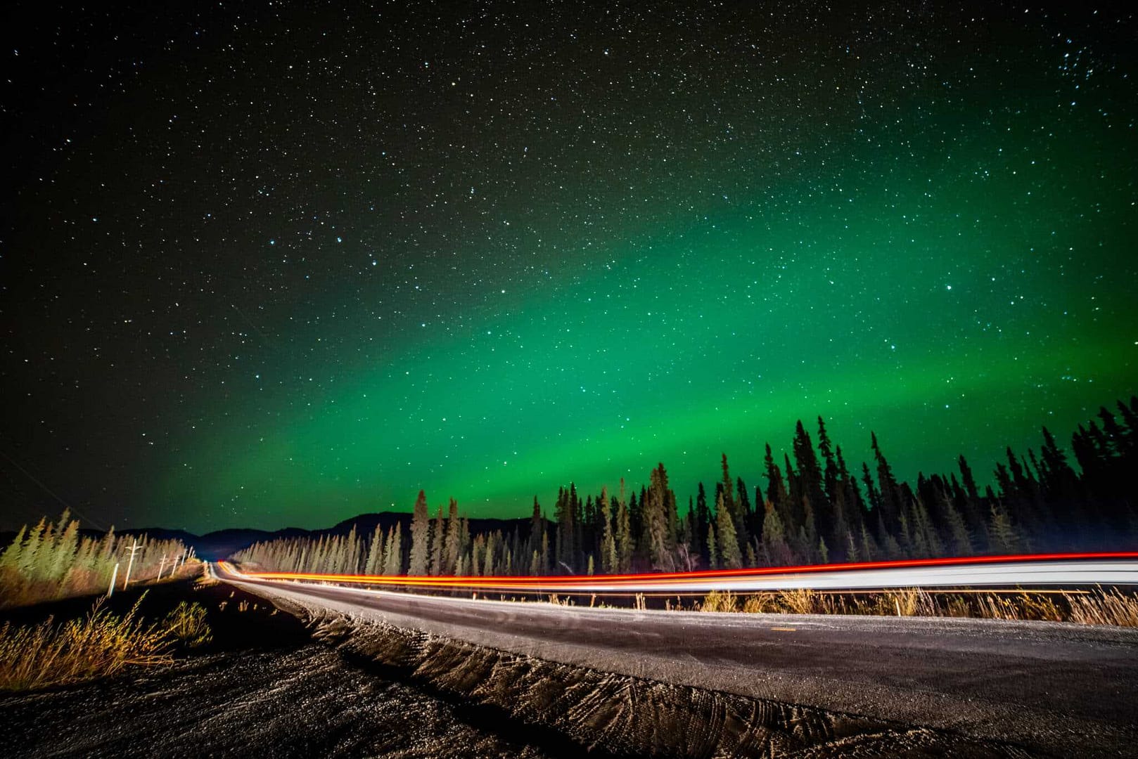 A green aurora bore over a road in the Yukon.