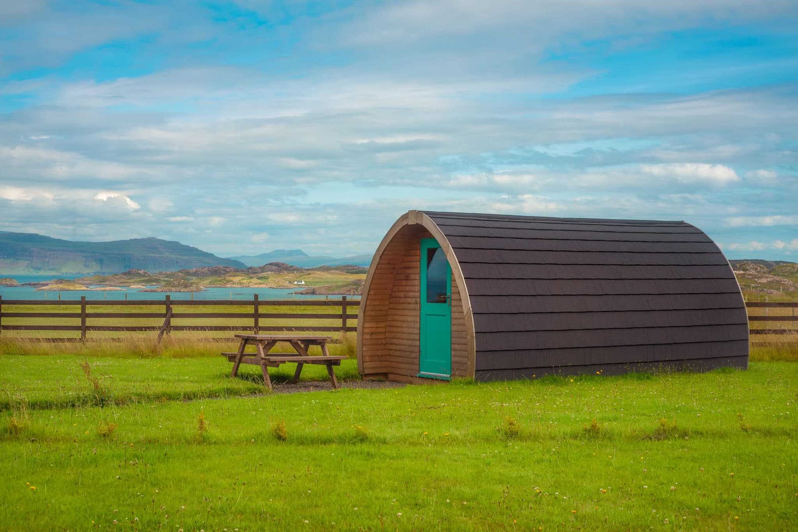 A proposed small cabin in a grassy field with a picnic table for glamping pods.