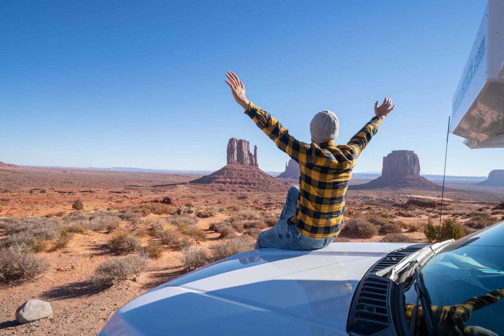 A man with his arms raised in front of his RV in Monument Valley, Arizona.