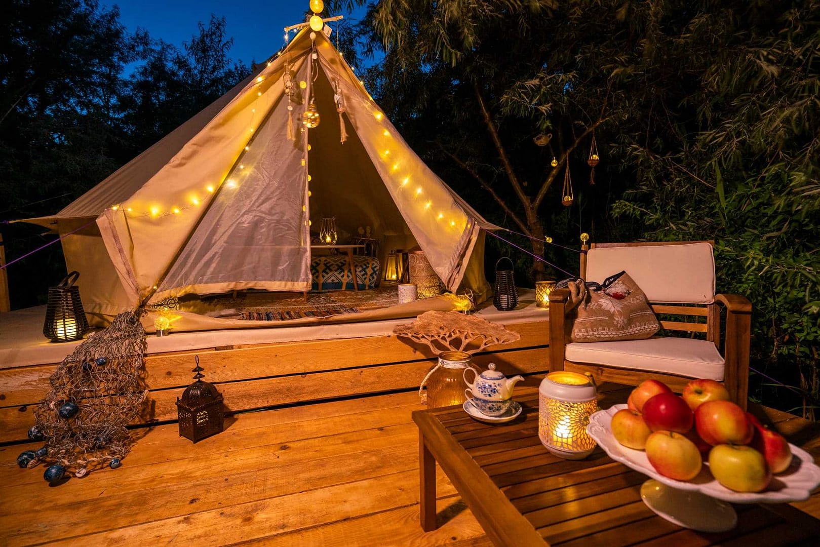 A teepee tent on a wooden deck at night.
