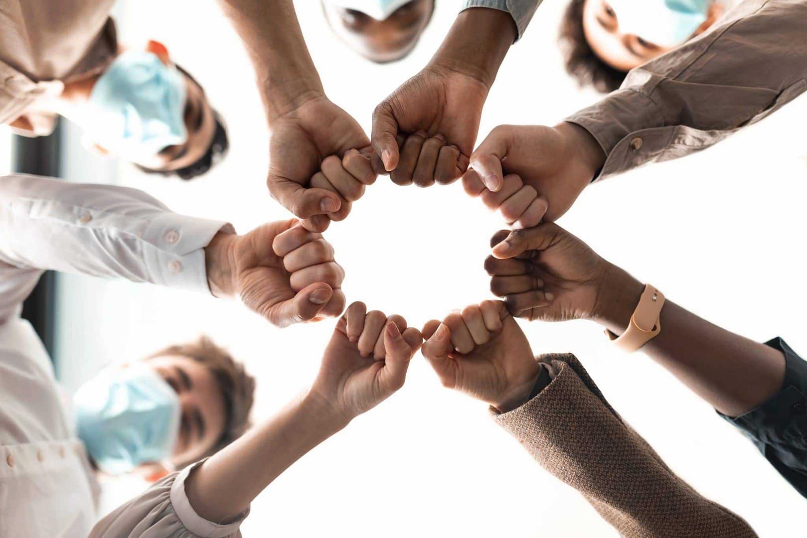 A group of people extending their hands in a circle, providing pandemic support.