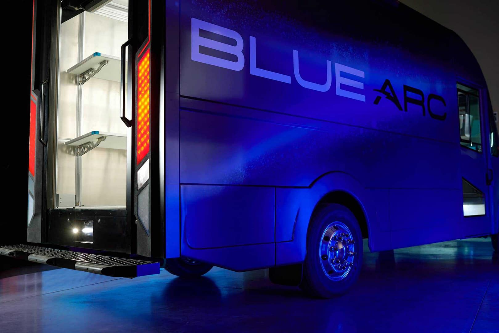 A Blue Arc EV Solutions truck is parked in a dark room.