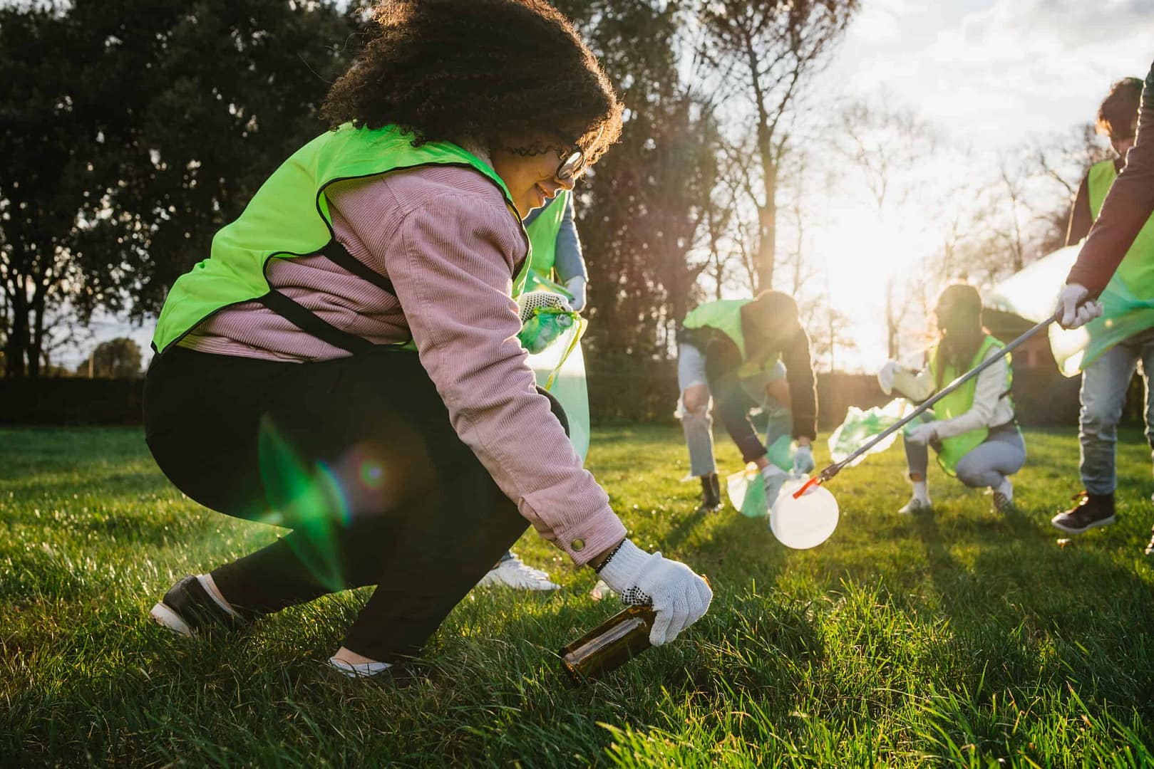 A group of people participating in the Annual I Love My Park event on May 7, picking up trash in a grassy area.