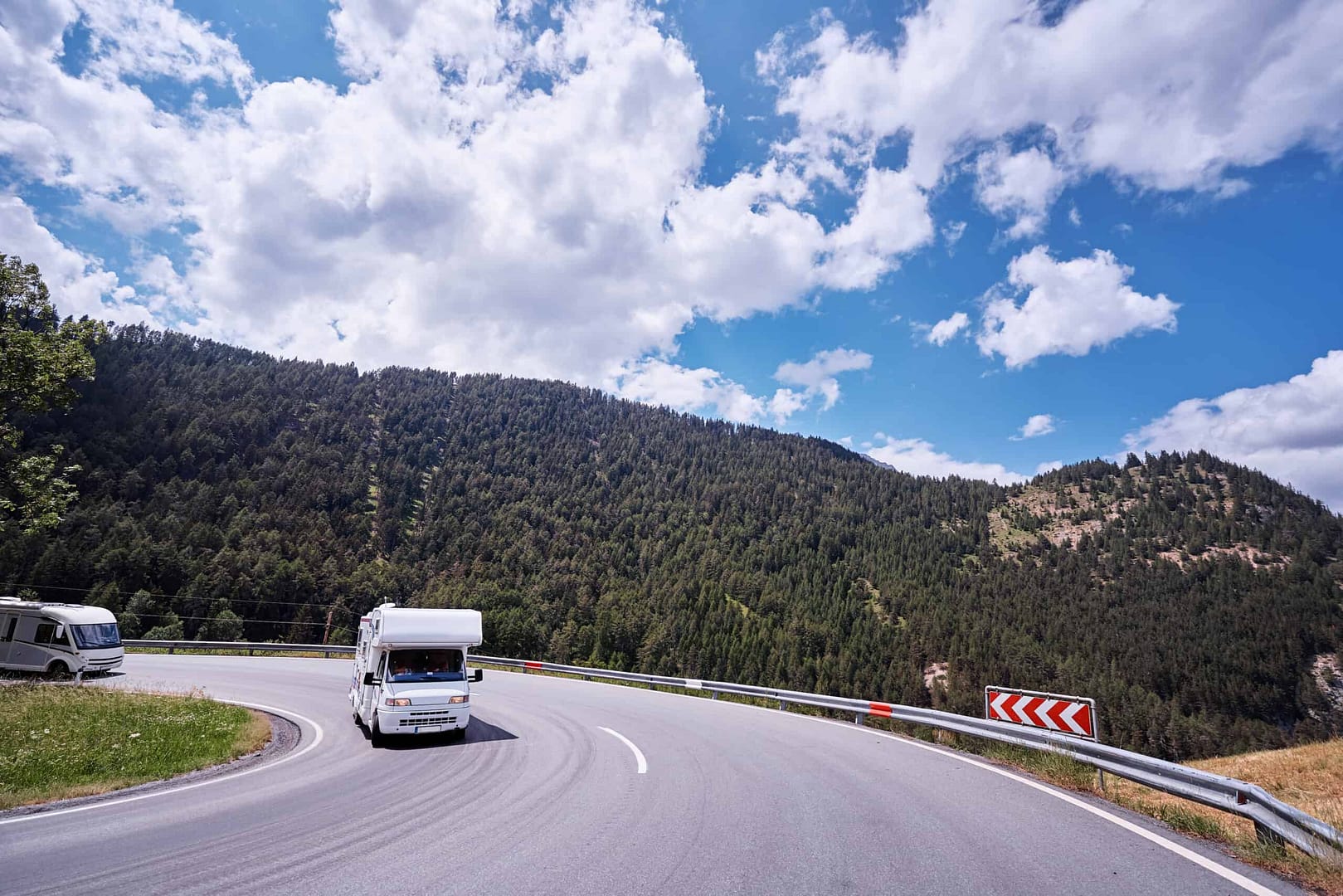 Two campers driving down a mountain road, ensuring road safety in the caravan industry.