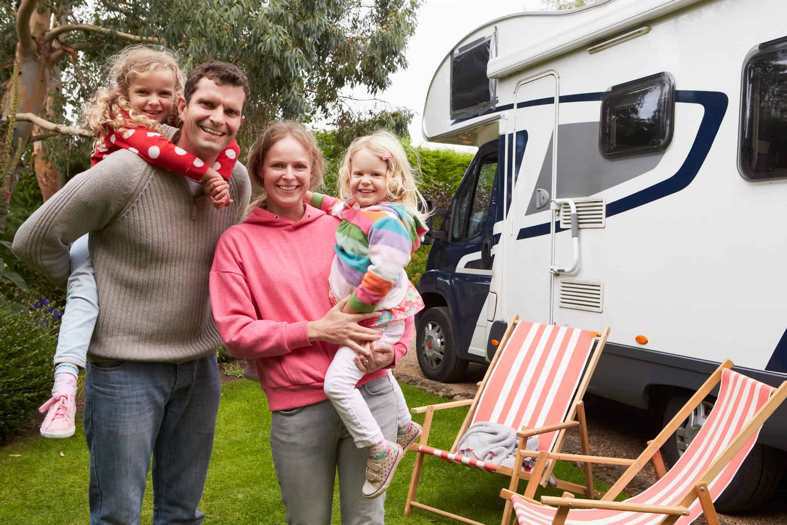A family enjoying a normal summer season at an RV resort in Central Alberta, standing in front of their RV.