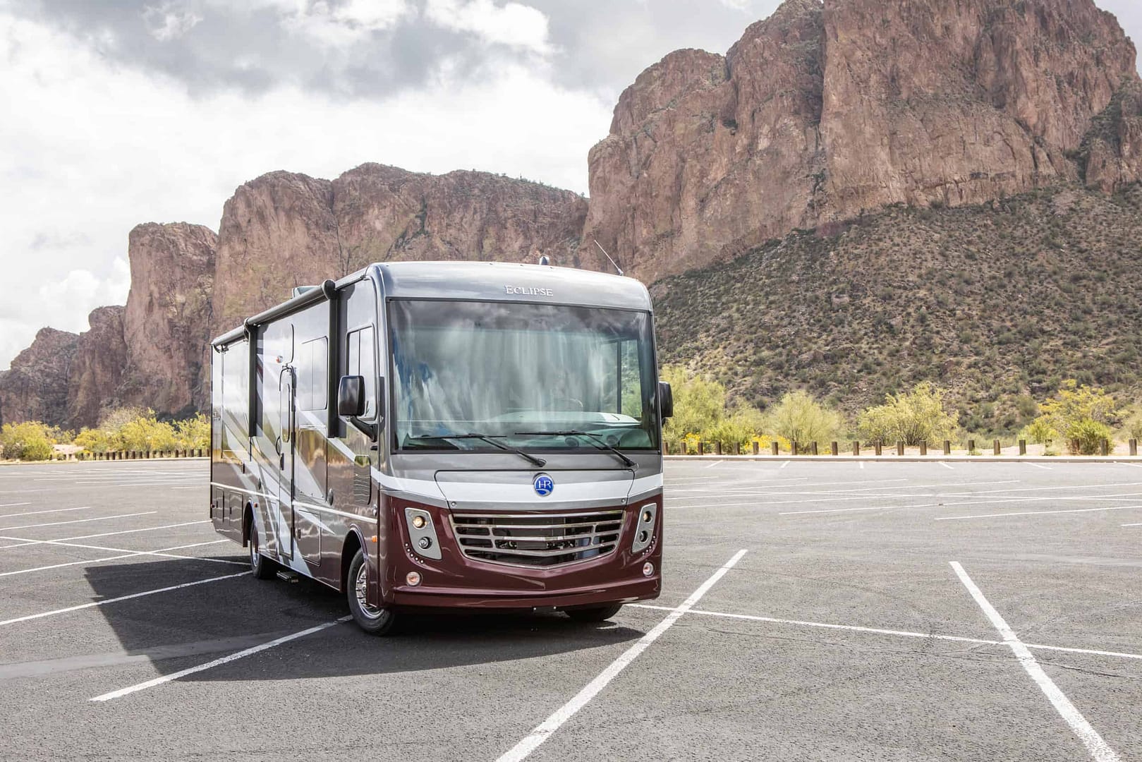 A Loaded Eclipse Motorhome parked in a parking lot with mountains in the background.