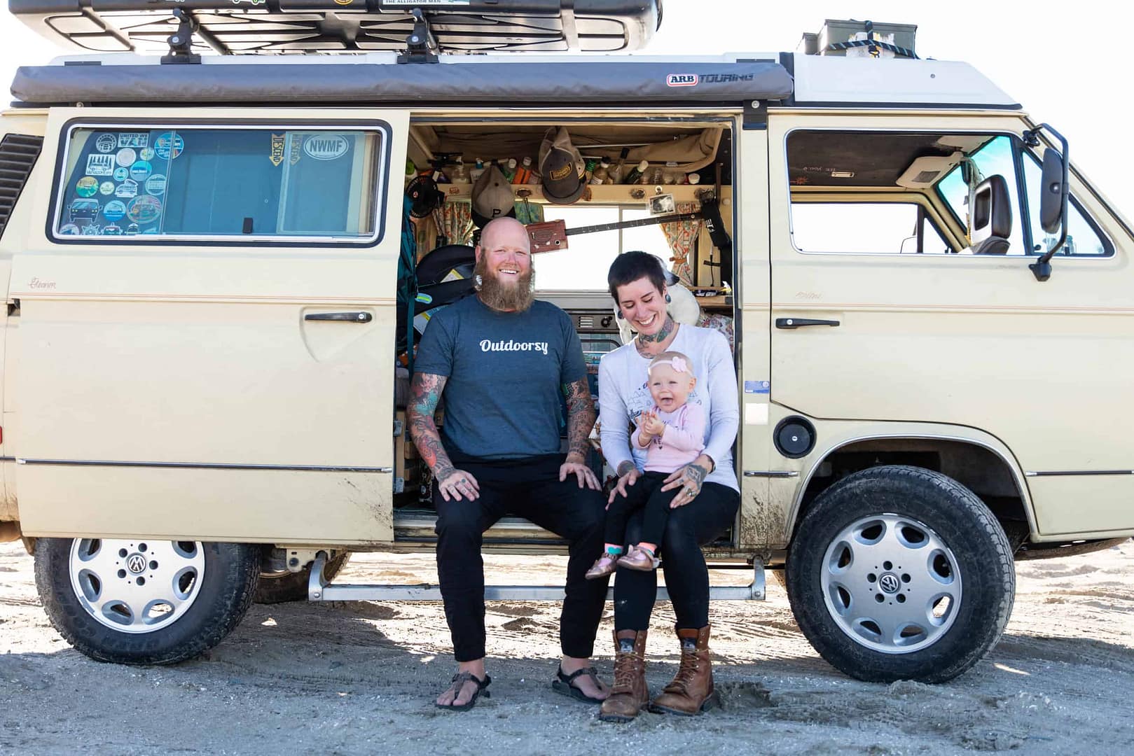 A family enjoys the outdoors in front of their built-in yellow VW bus.