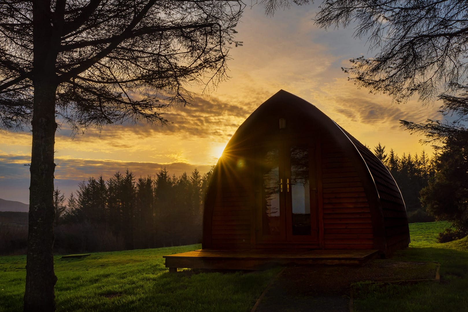 A small Gleddoch Hotel sitting on a grassy field at sunset.