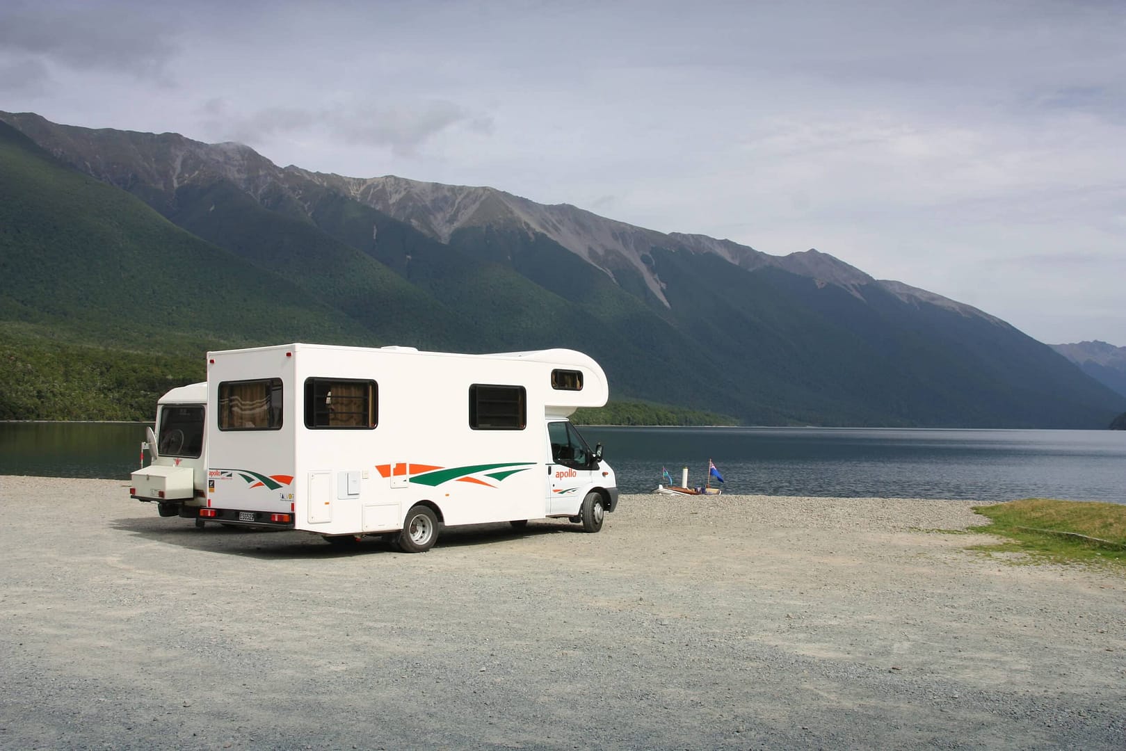 An Aussie-made white RV is parked next to a stream.