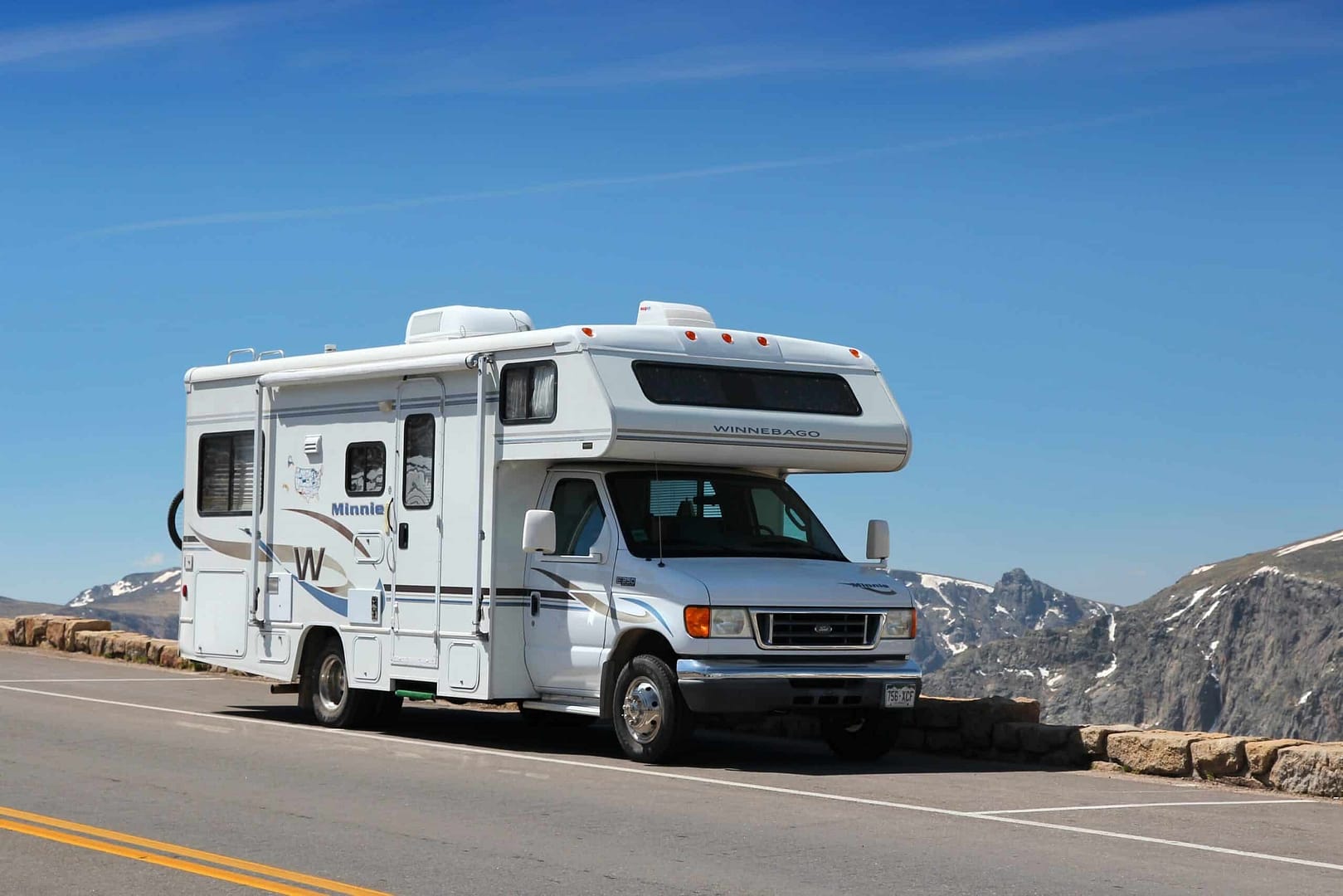 A white Winnebago Industries rv parked on the side of a mountain road.