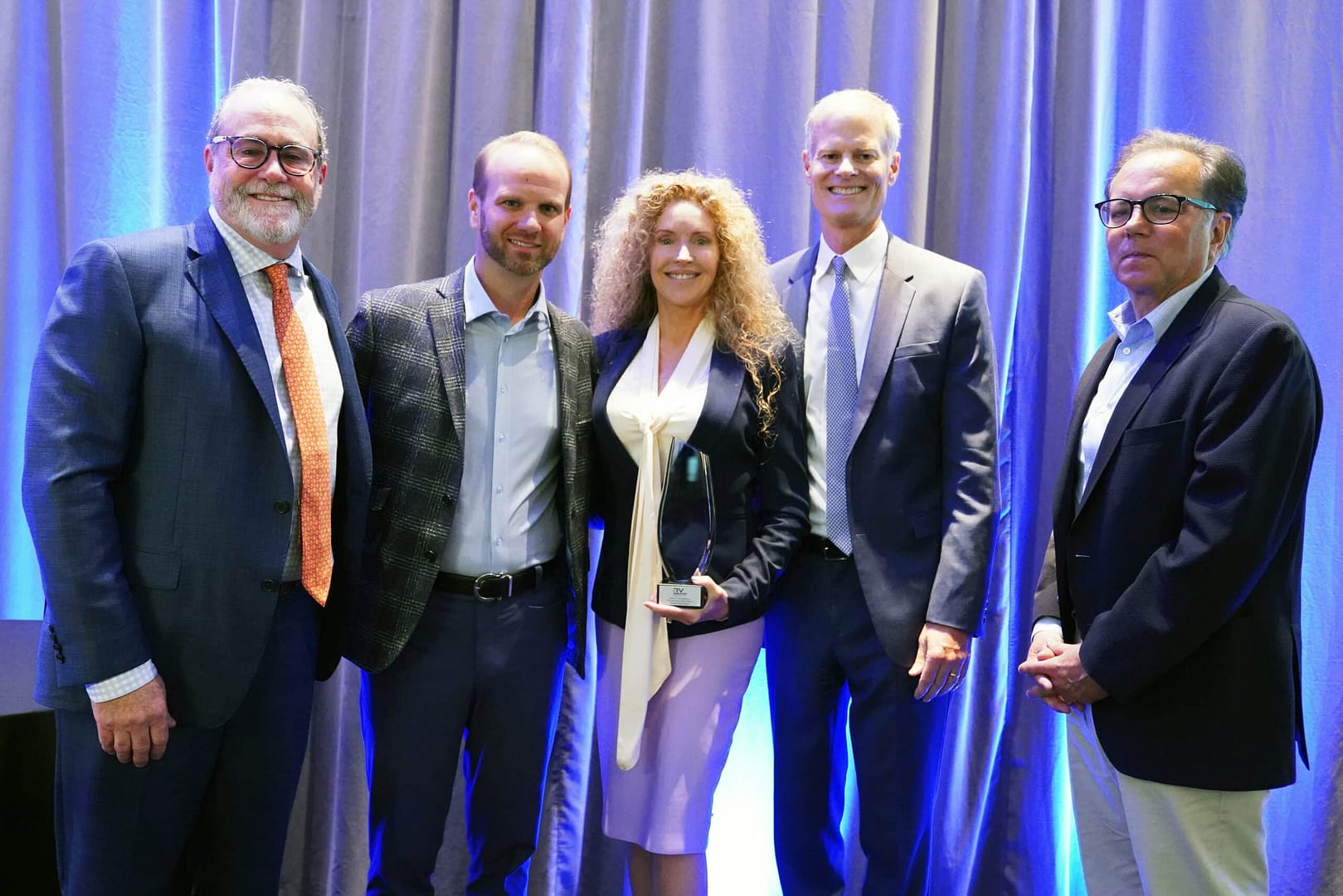 A group of RV industry leaders posing for a photo with an award, showcasing their trailblazing achievements.
