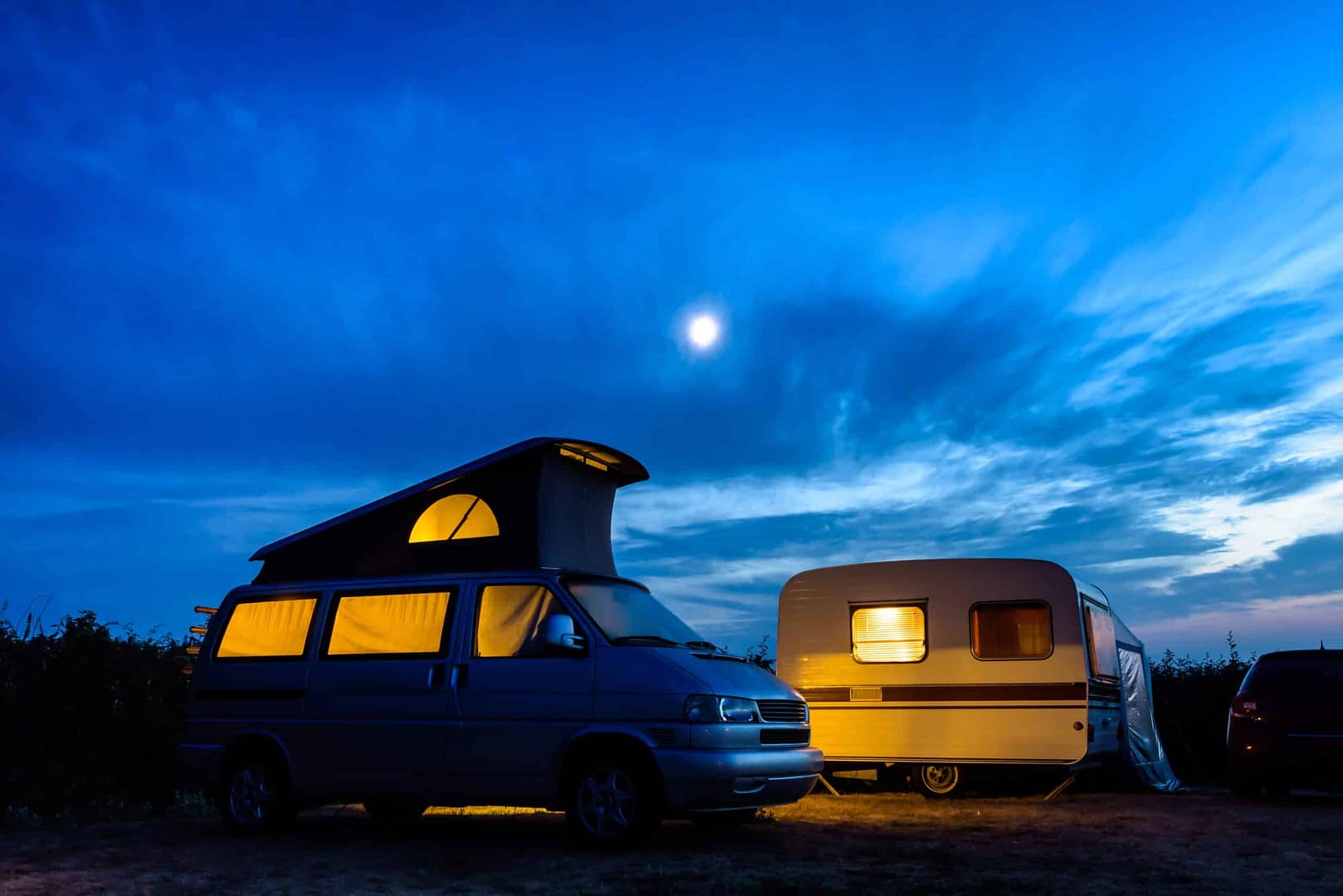 Two electric camper vans parked in a field at night, representing the sustainable revolution.