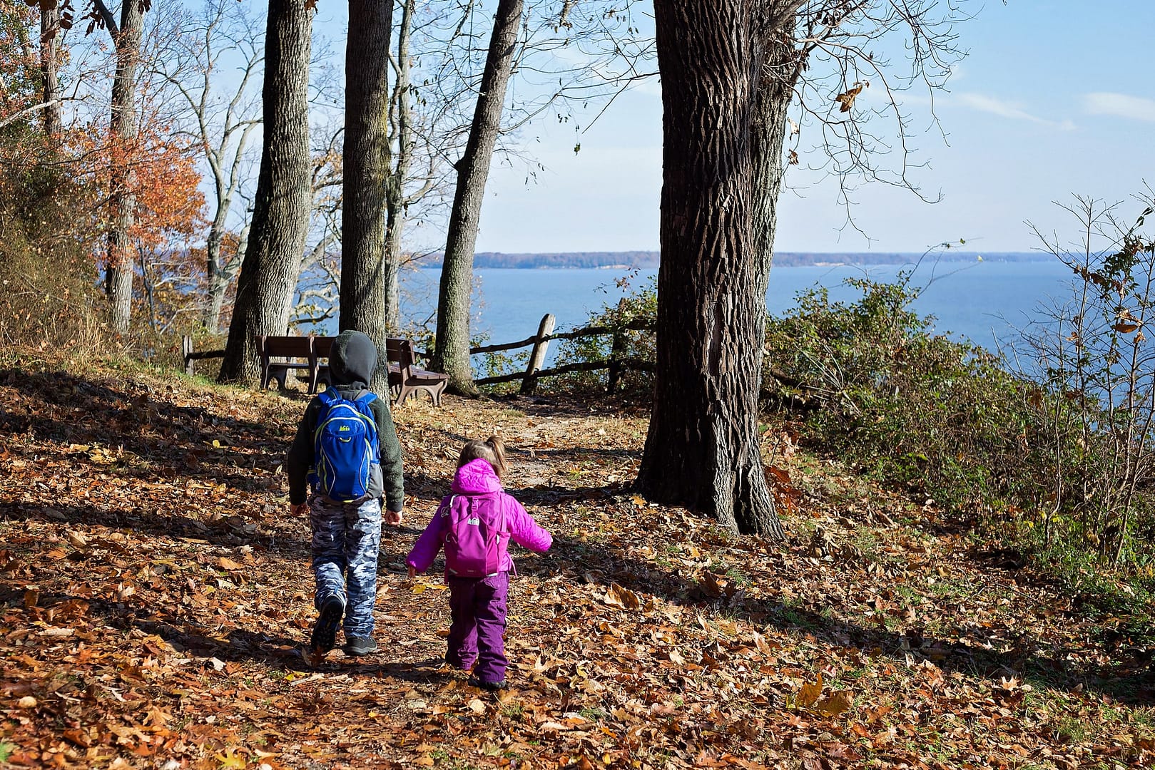 Two children enjoying the outdoors while walking down a trail near a body of water in Virginia State Parks.