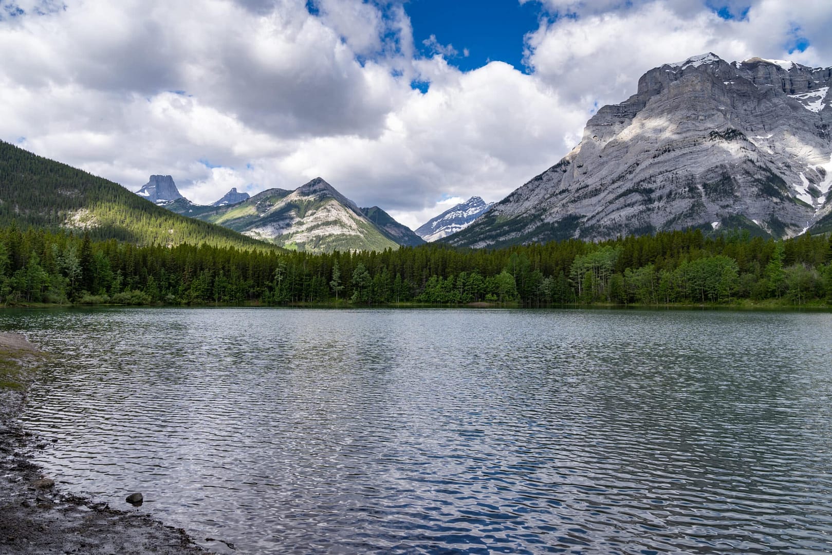 A lake surrounded by mountains and trees in Kananaskis, Alberta.