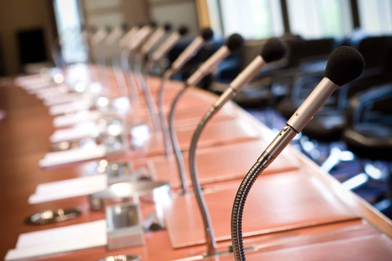 Row of microphones set up on a long table in a conference room, suggesting preparation for a meeting or discussion by the Oneonta Planning Board.