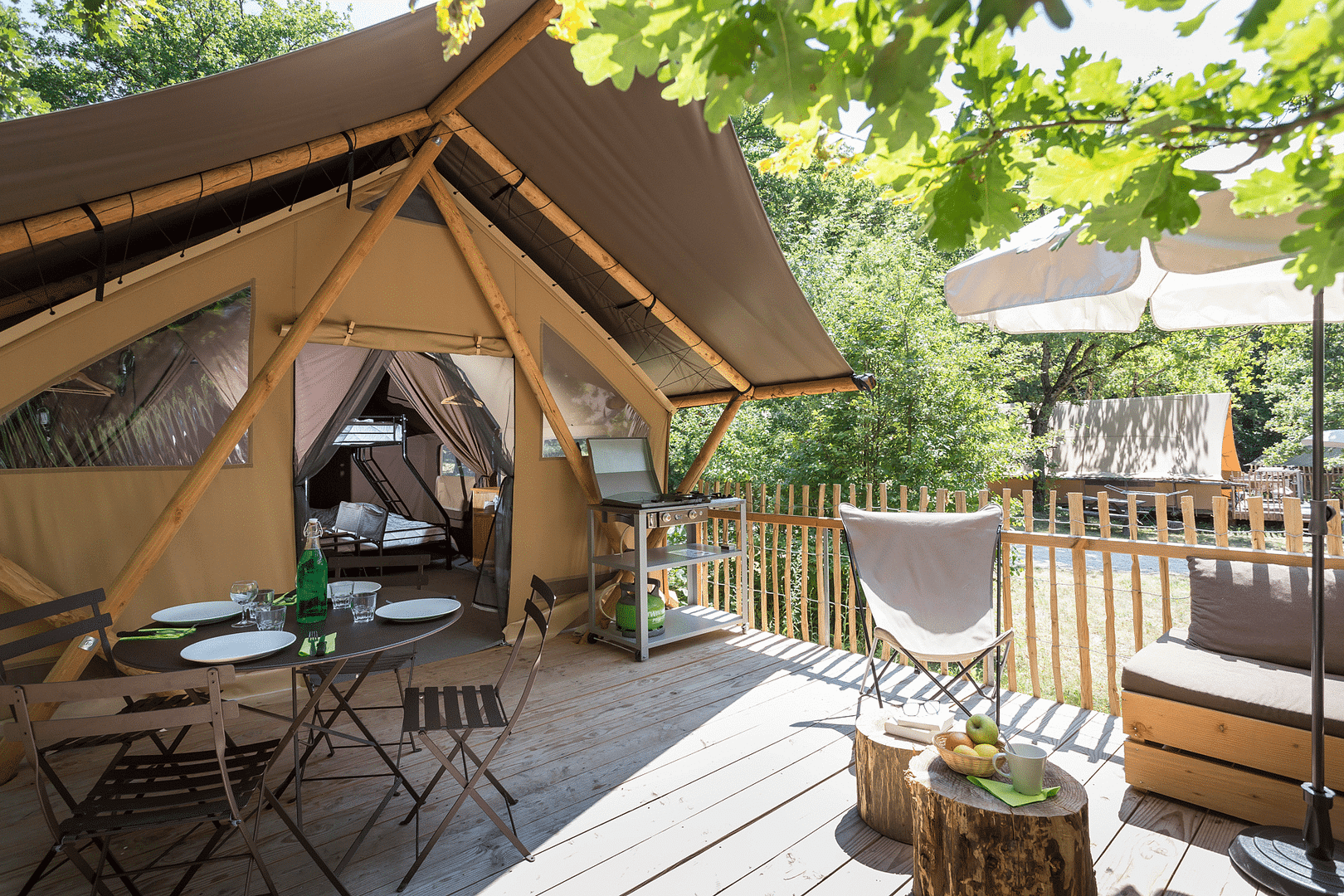 A tepee tent on a wooden deck with a table and chairs.