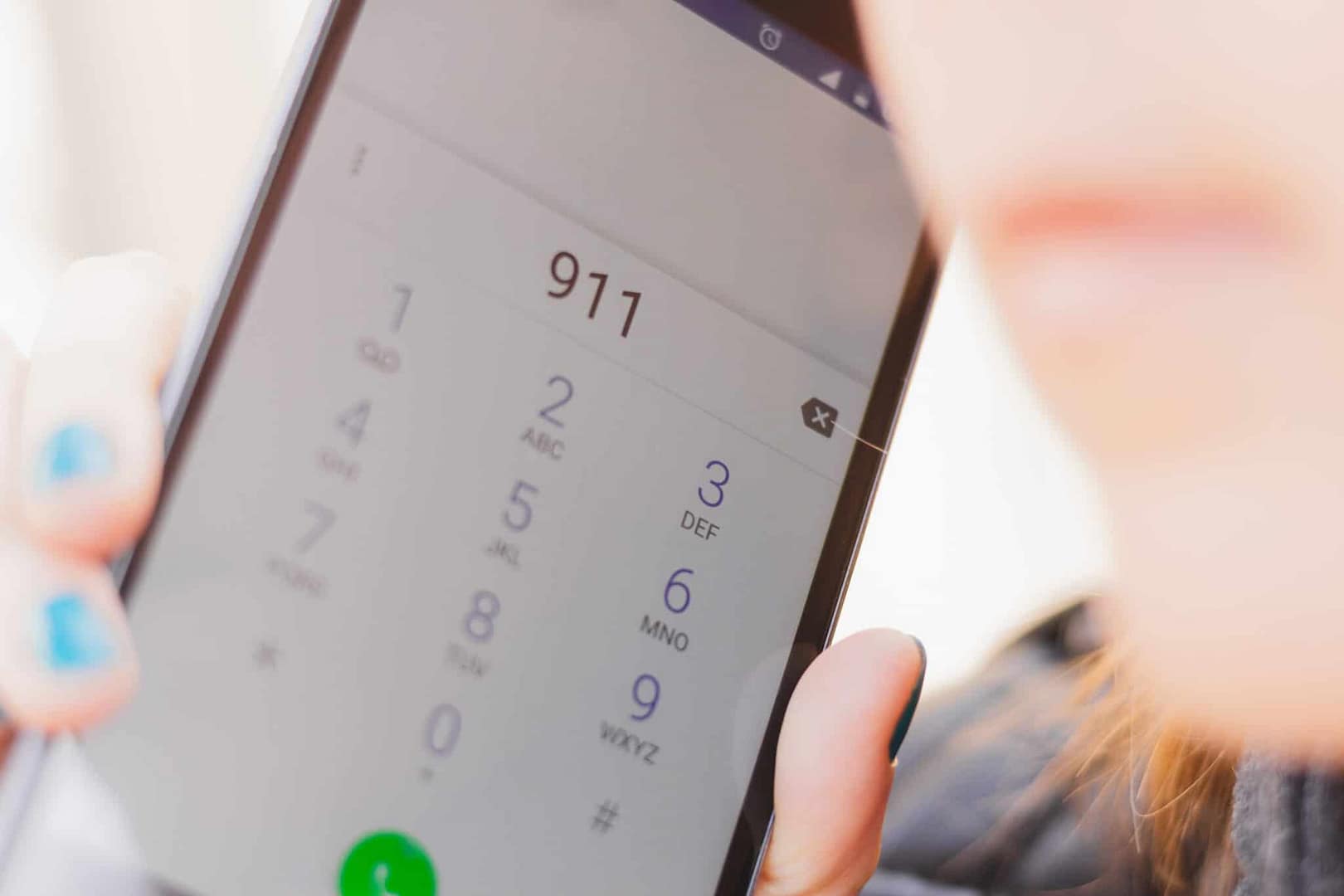 A woman holding up a cell phone with a politically-themed Florida 9-1-1 number on it.