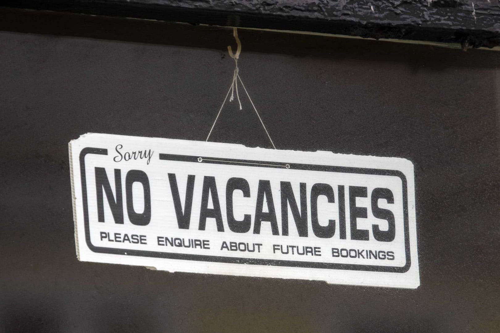 A sign that says no vacancies hangs on the side of a building in a campground, showcasing the campground crunch dilemma.