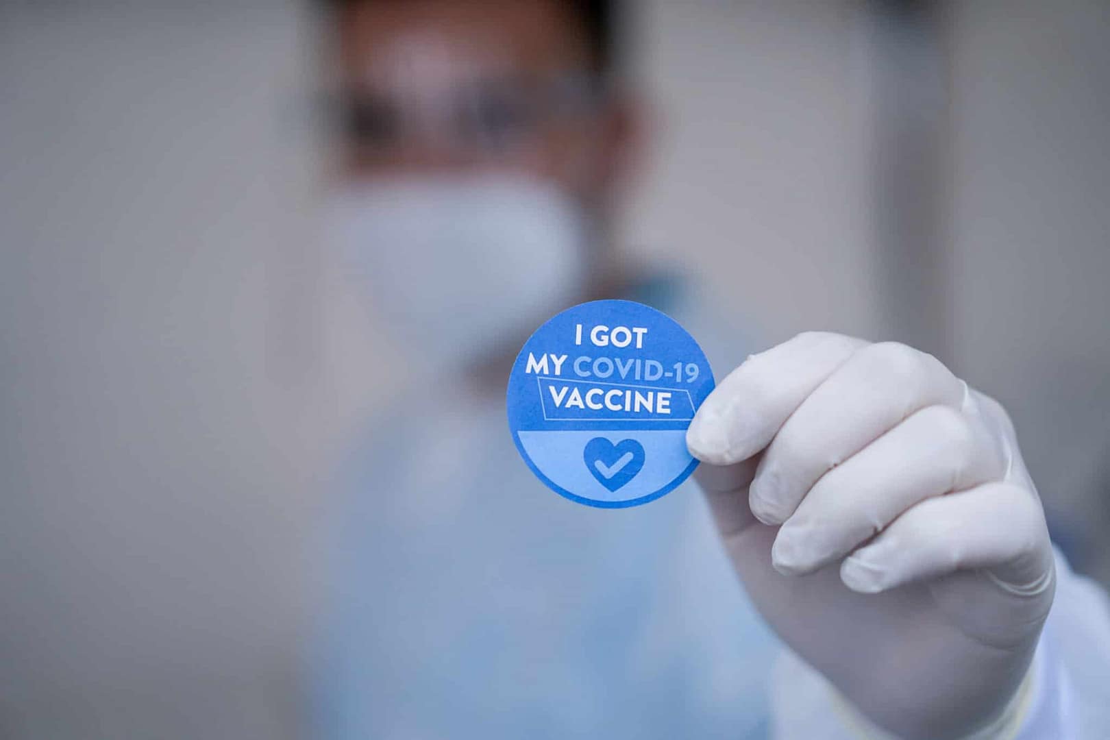 At a trade show in Missouri, a doctor proudly holds up a blue badge that says lost medical vaccine, providing Covid Vaccination Proof.