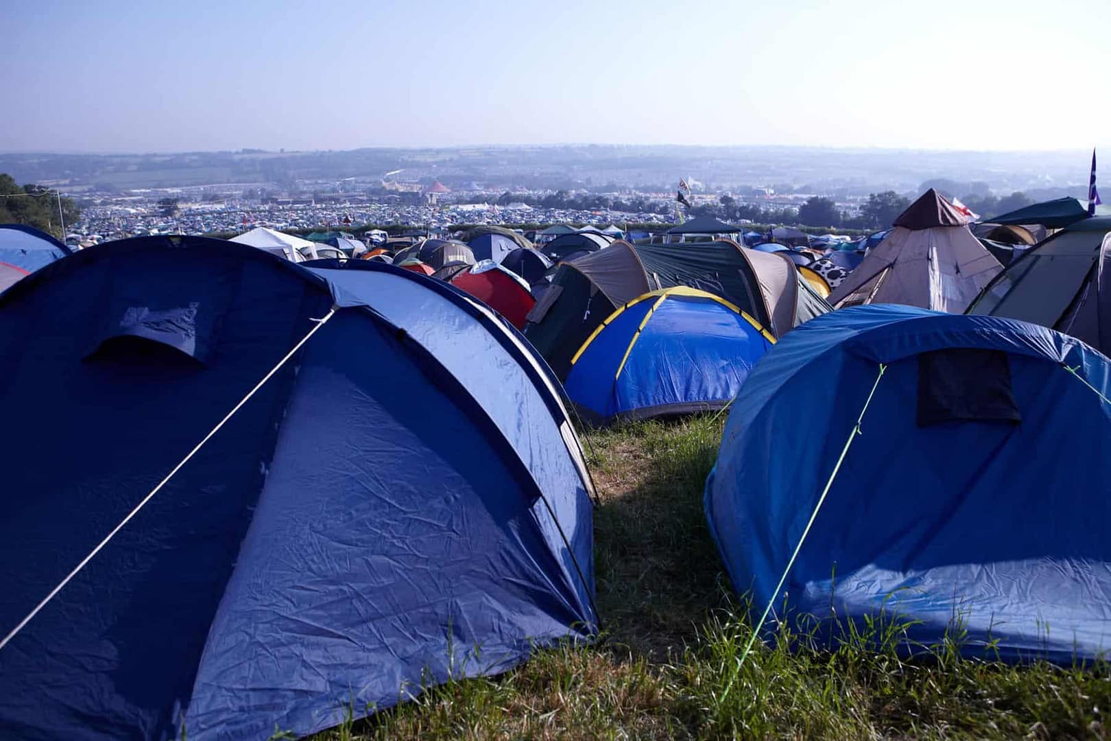 Campers pitch tents on a grassy field during the pandemic.